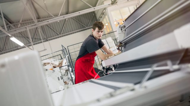 Worker working in fabric industry Worker working on fabric spreading machine in fabric industry
